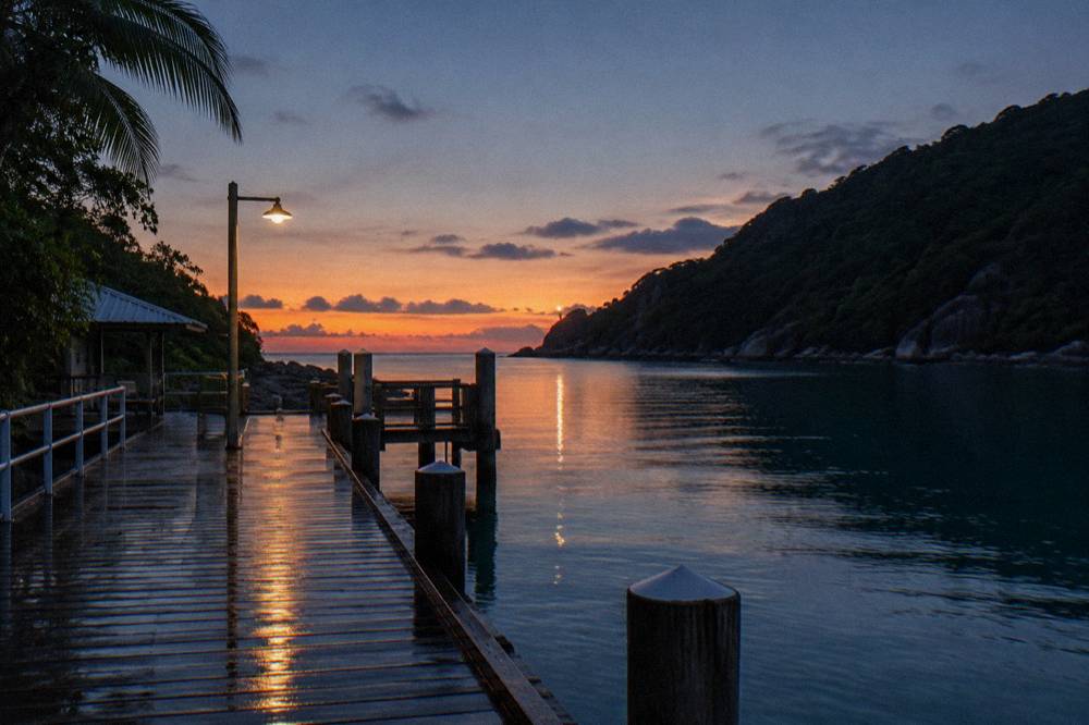 Sheltered tropical bay with a jetty and forested headland