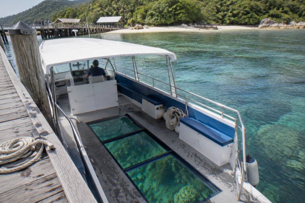A glass-bottom boat drifting over a coral reef visible through clear water