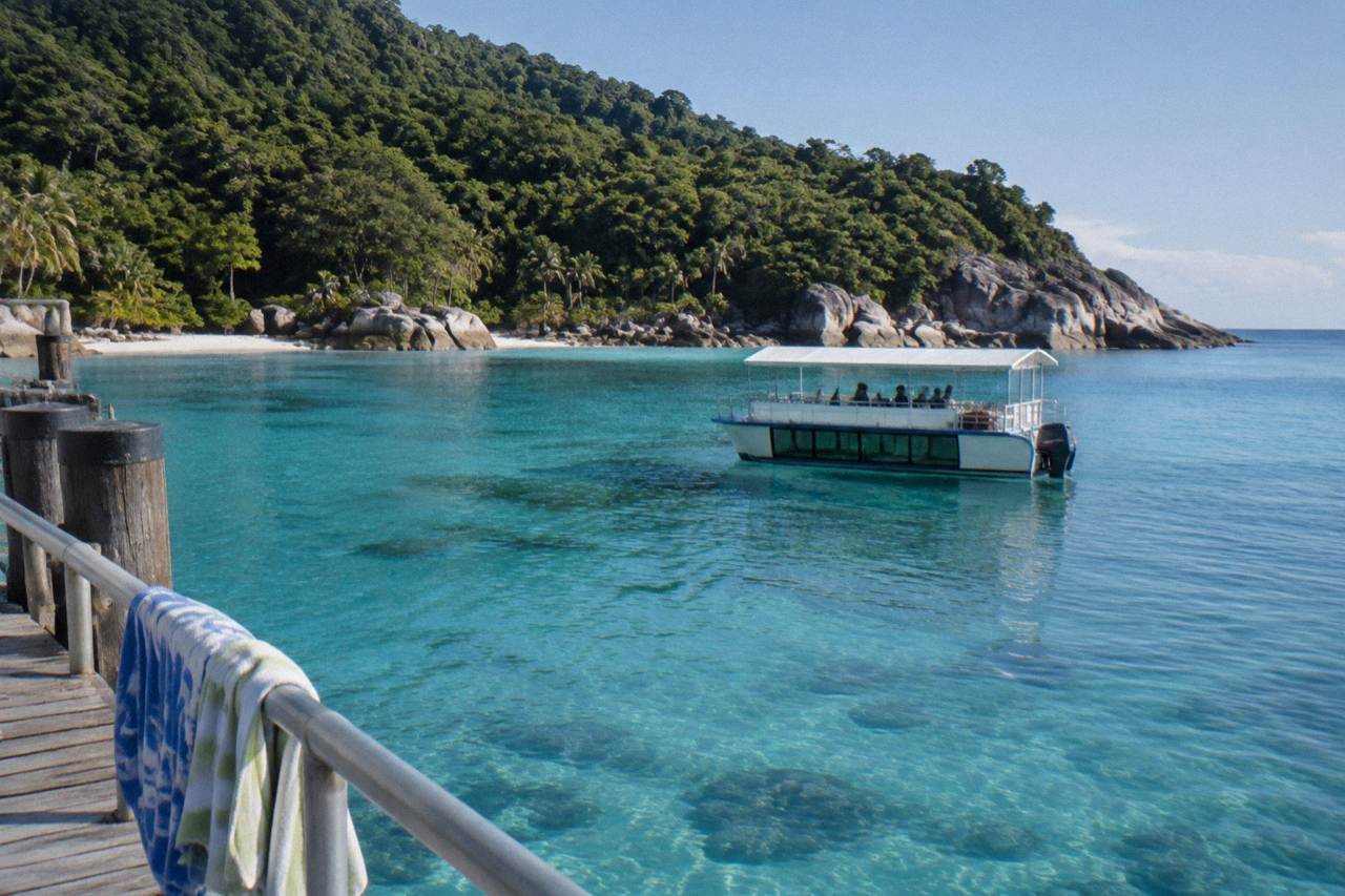 A glass bottom boat drifting over calm turquoise water above a fringing coral reef