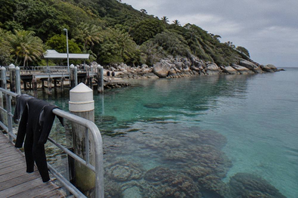 Calm sheltered bay with clear shallow water over coral and rocky headland at a tropical island