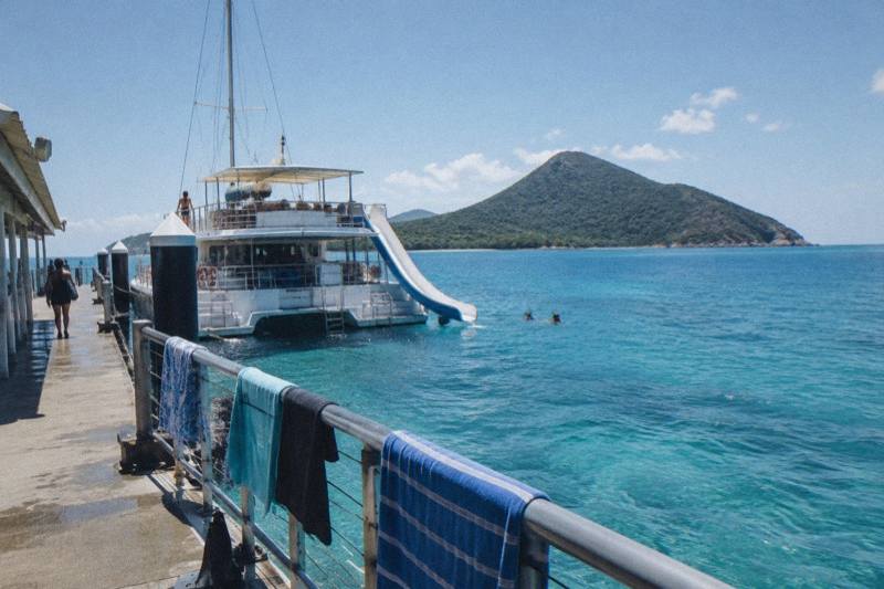 A catamaran moored at a Great Barrier Reef pontoon with Fitzroy Island on the horizon