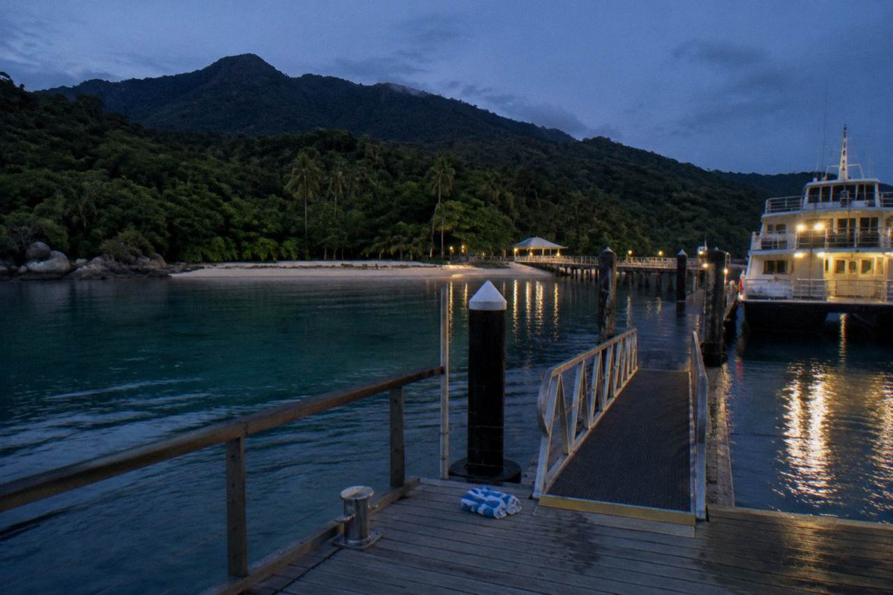 Turquoise water and coral beach at a tropical island jetty with a moored ferry