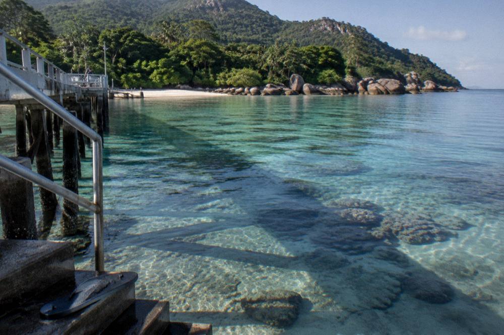 Morning light across calm bay water with coral visible below the surface