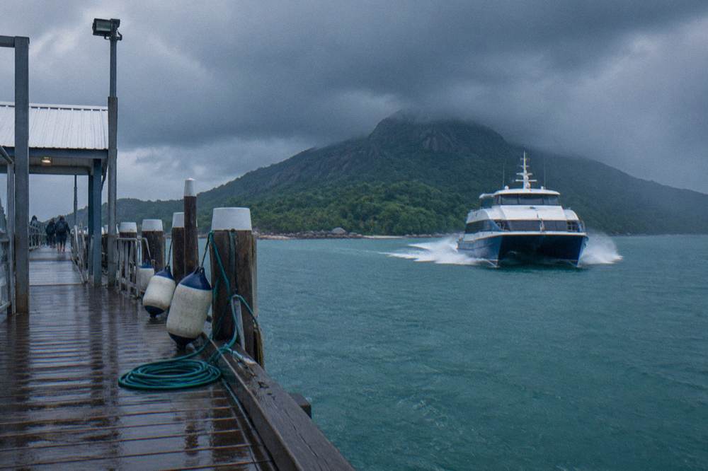 Fast catamaran ferry approaching a tropical island jetty