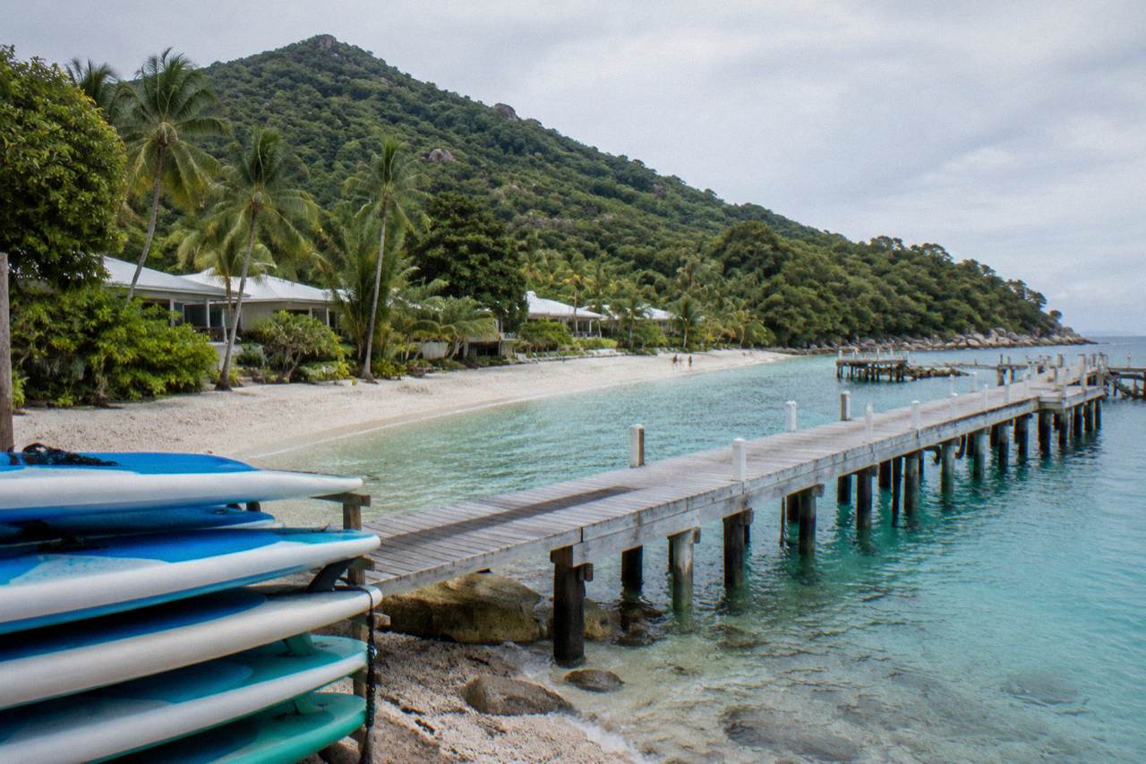 Welcome Bay at Fitzroy Island with the resort buildings and jetty behind a coral beach