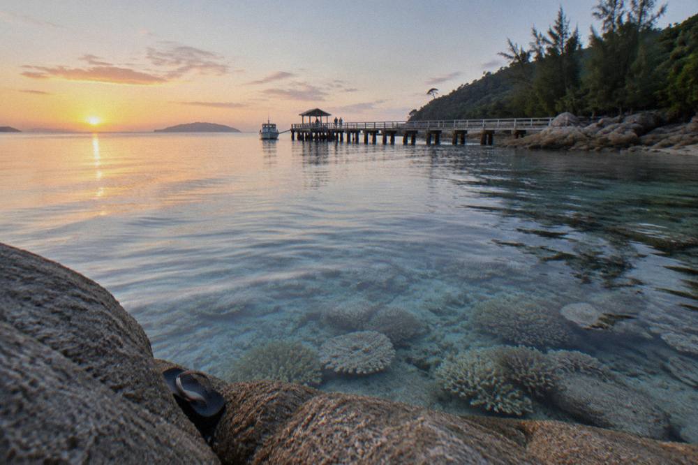 Shallow clear water over coral near a granite boulder shoreline