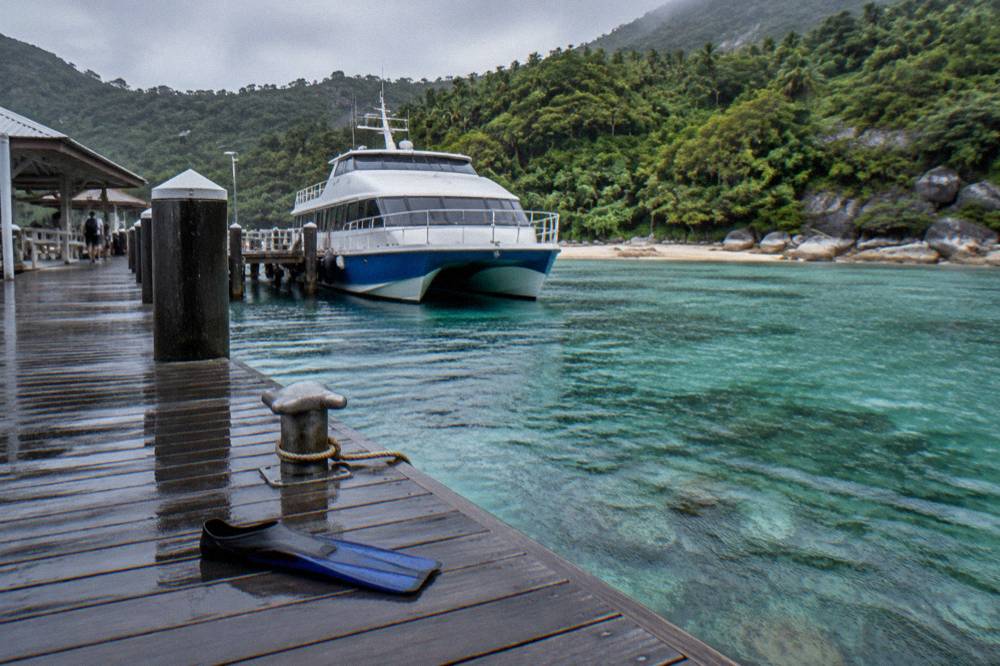A ferry moored at a timber jetty above clear green water