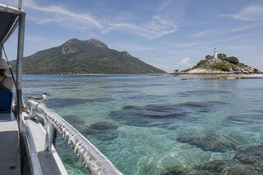 Two tropical islands seen from the water across calm reef shallows