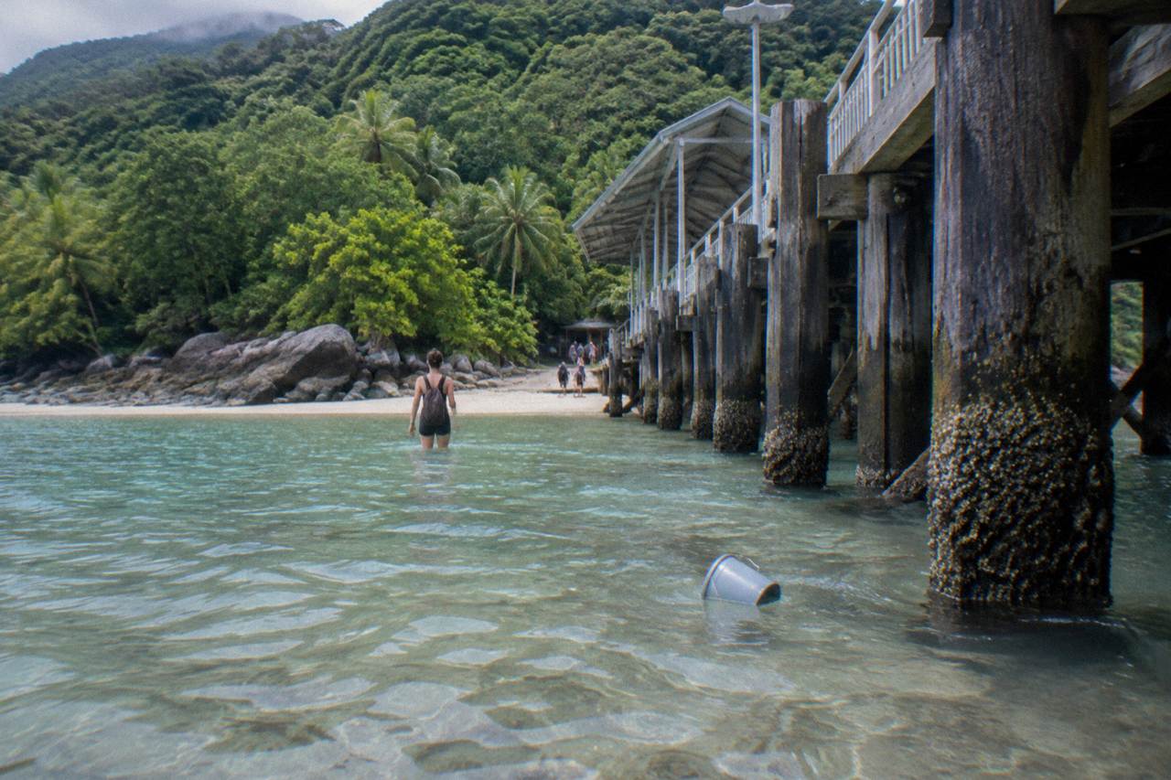 Calm shallow water over coral sand at a tropical island beach with rainforest behind