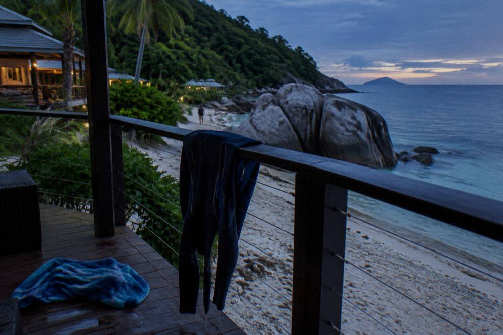 A full body lycra stinger suit drying on a rail beside a beach