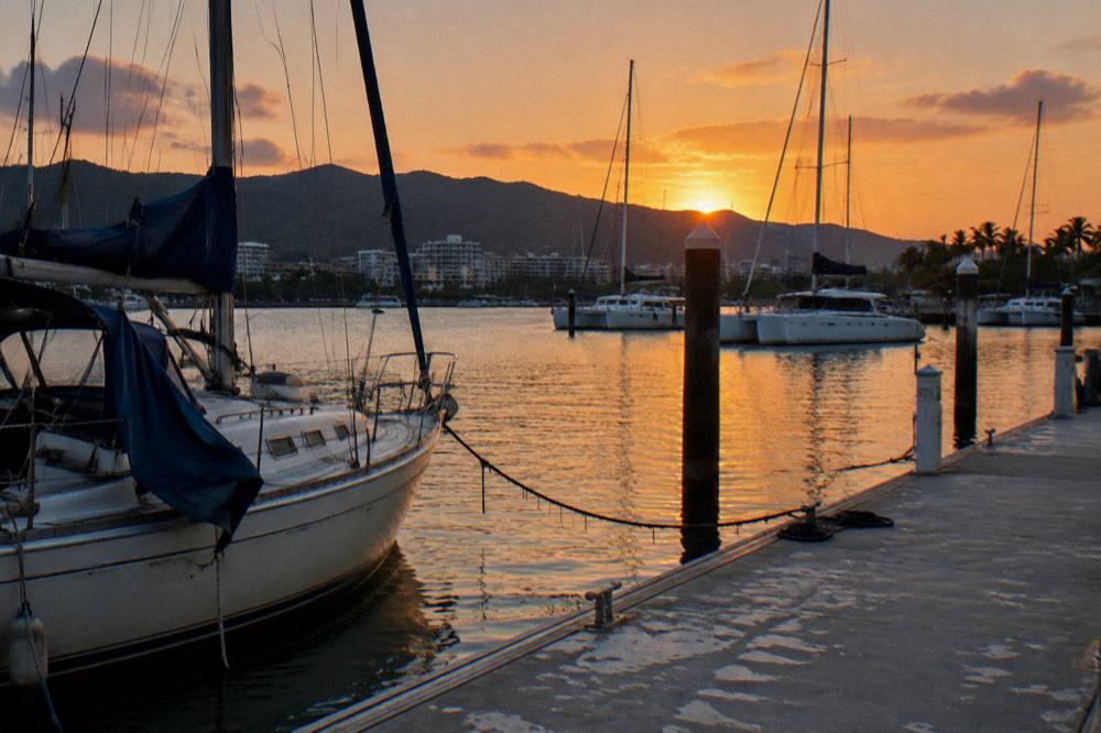 Sunset over Cairns city skyline and harbour water with hills behind