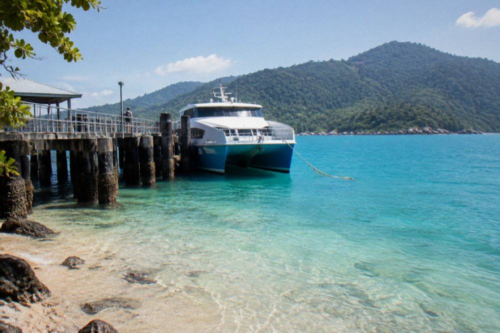 Fast catamaran ferry moored at a tropical island jetty in bright daylight